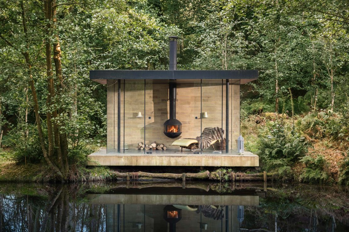 Pequeno ambiente integrado à natureza com lareira e espaço para leitura e descanso.